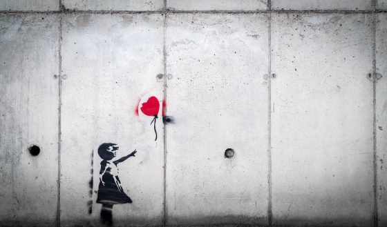 graffito silhouette of girl reaching for red heart on a string