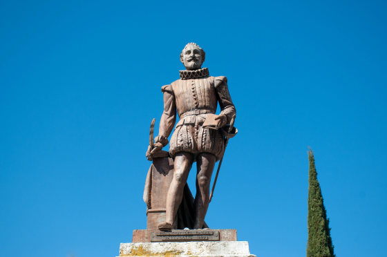 A statue of Garcilaso de la Vega against a clear blue sky