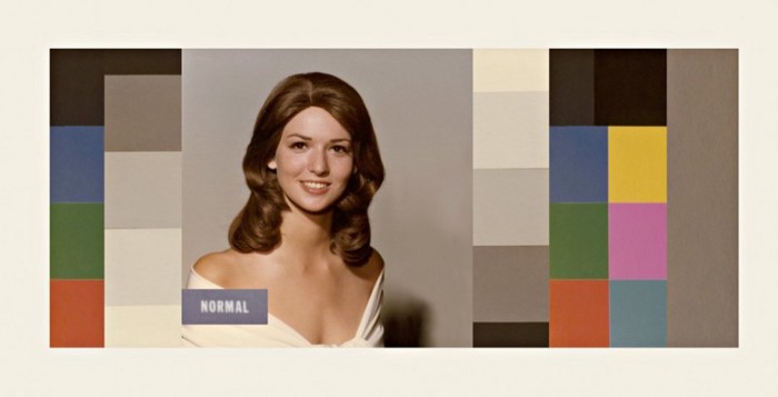 A white woman with wavy brown hair. Surrounding the picture are blocks of color.