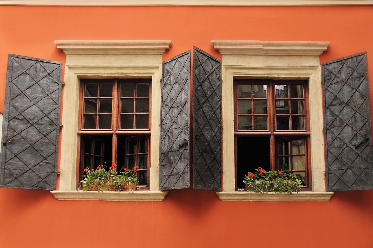 Two matching windows, side by side, with matching shutters. There is a flowerpot in each window.