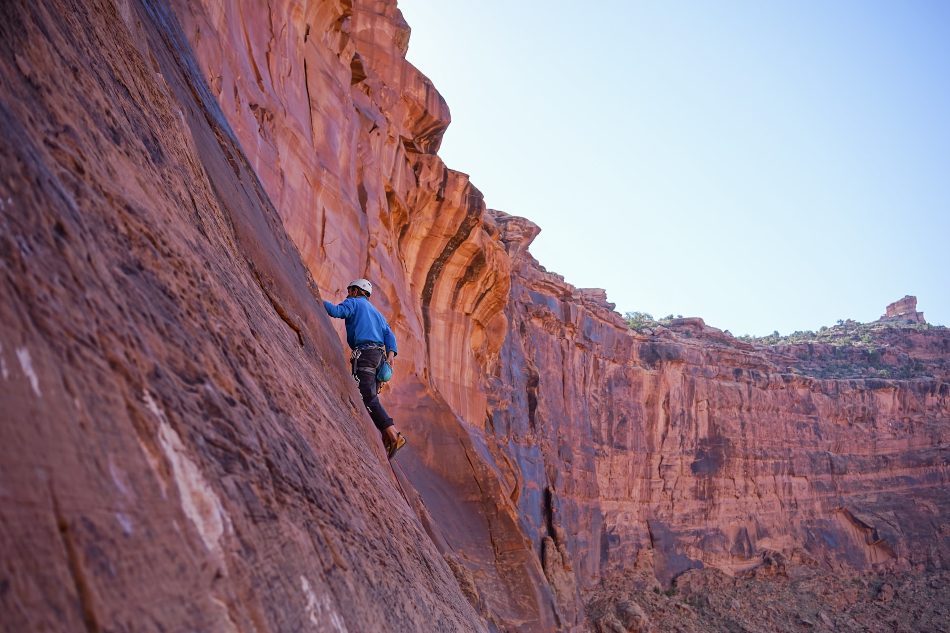 A person climbs a sheer cliff.