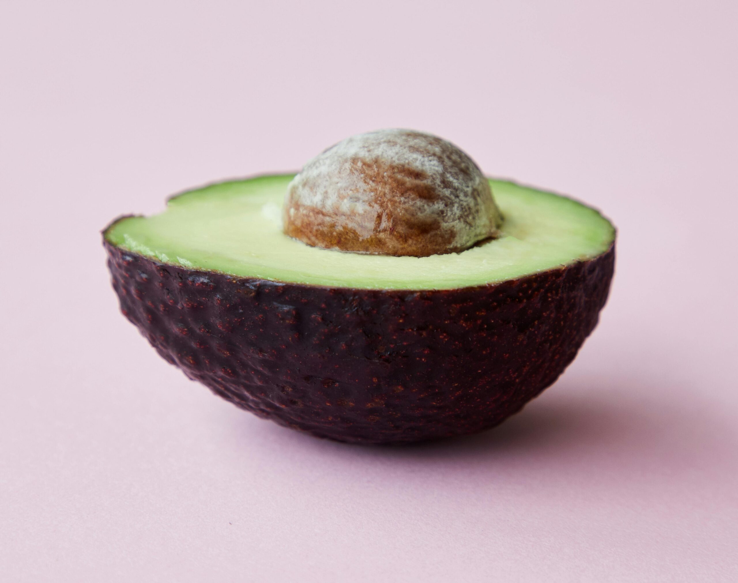 avocado, split in half. The bottom half is the entire avocado, and the top half shows the top part of the seed.