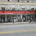 Street view of the F. W. Woolworth building in Greensboro, North Carolina. There are a dozen people standing on the sidewalk in front of the building.