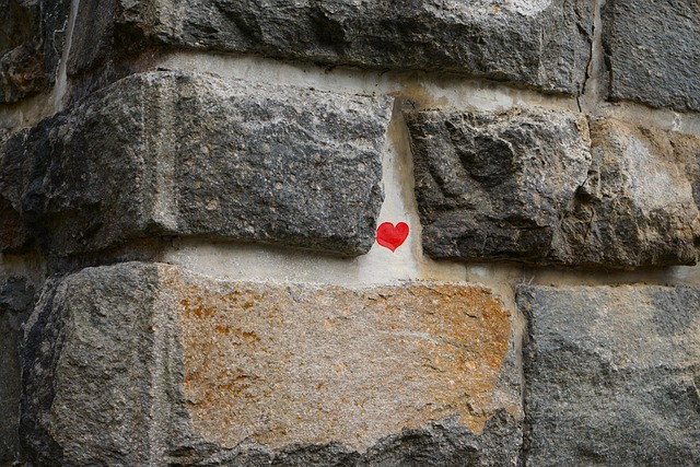 A stone wall. In between two of the stones is the drawn image of a heart icon.